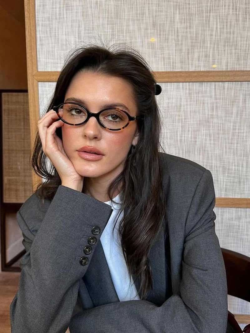 A woman wearing minimalist blue-light reading glasses while relaxing at home.