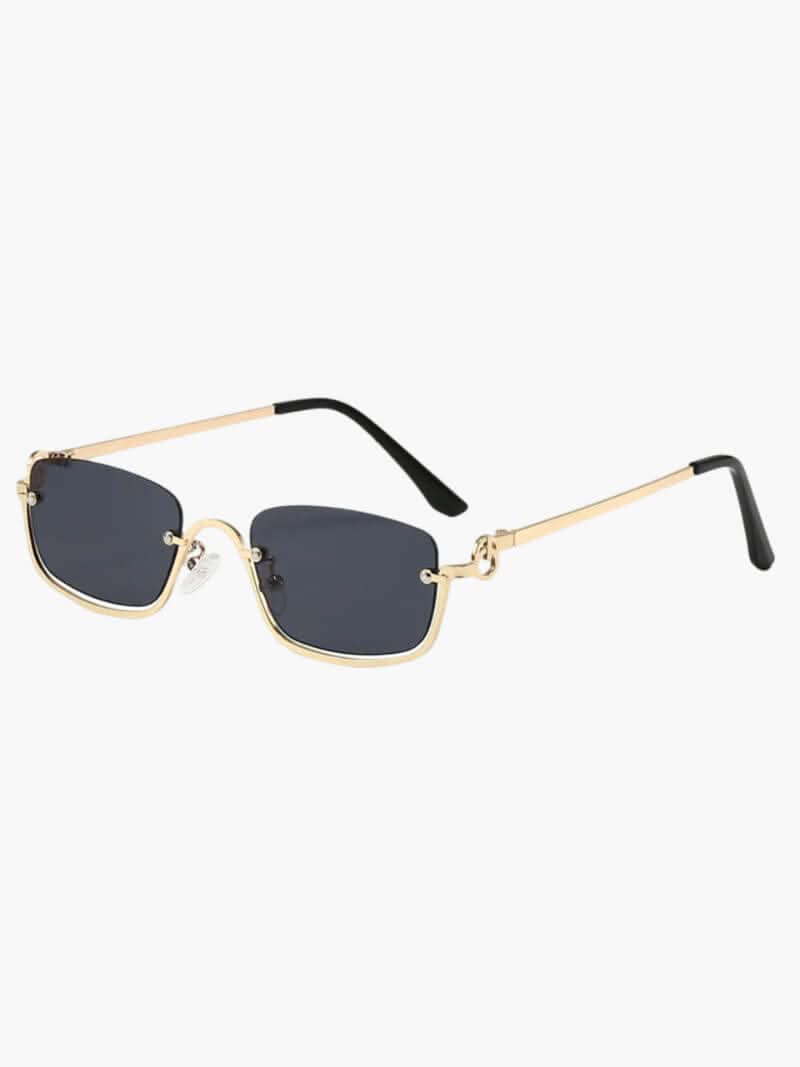 A woman wearing sleek rectangular gold-finish sunglasses on a bright city day.