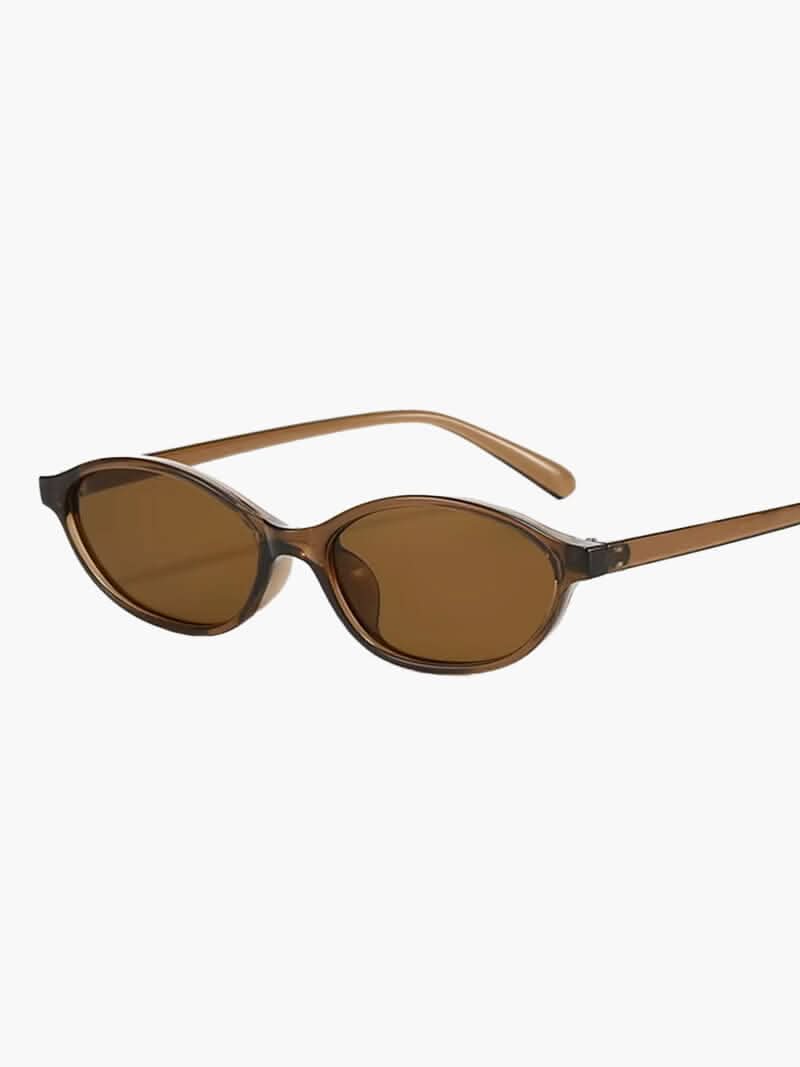 A woman by the sea wearing classic oval vintage sunglasses, relaxed and elegant in the sun.