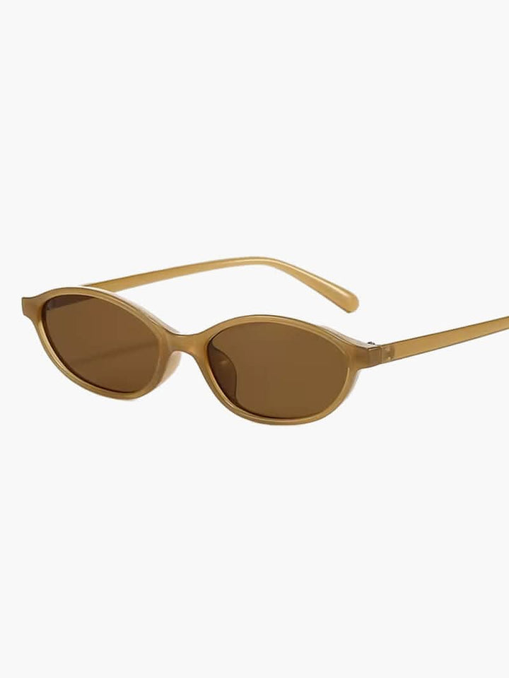 A woman by the sea wearing classic oval vintage sunglasses, relaxed and elegant in the sun.