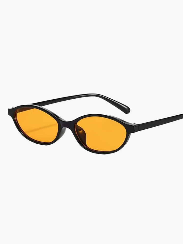 A woman by the sea wearing classic oval vintage sunglasses, relaxed and elegant in the sun.