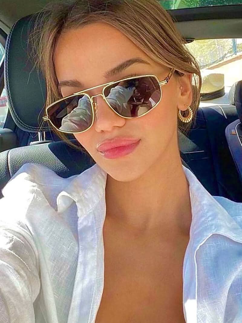 A woman wearing lightweight gold polarised sunglasses on a bright coastal day.