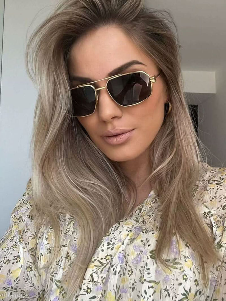 A woman wearing lightweight gold polarised sunglasses on a bright coastal day.