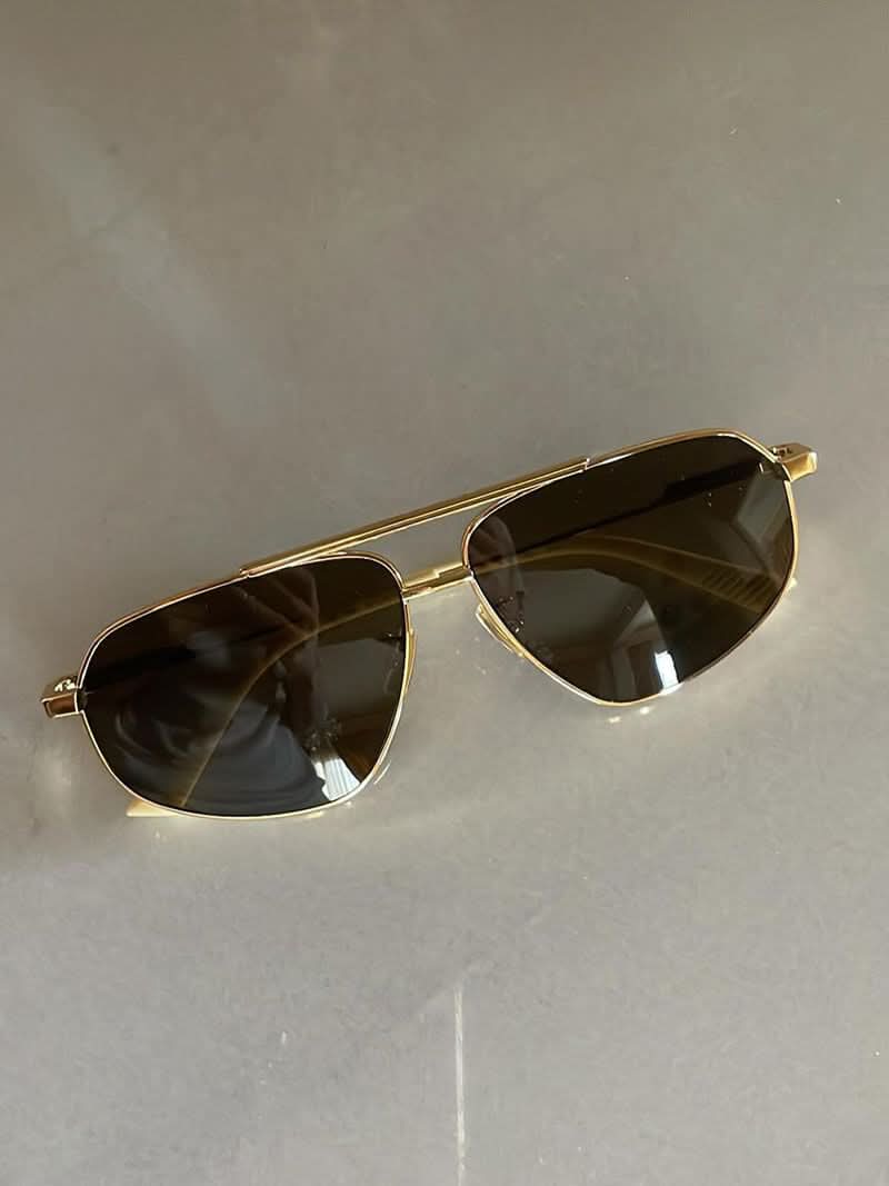A woman wearing lightweight gold polarised sunglasses on a bright coastal day.