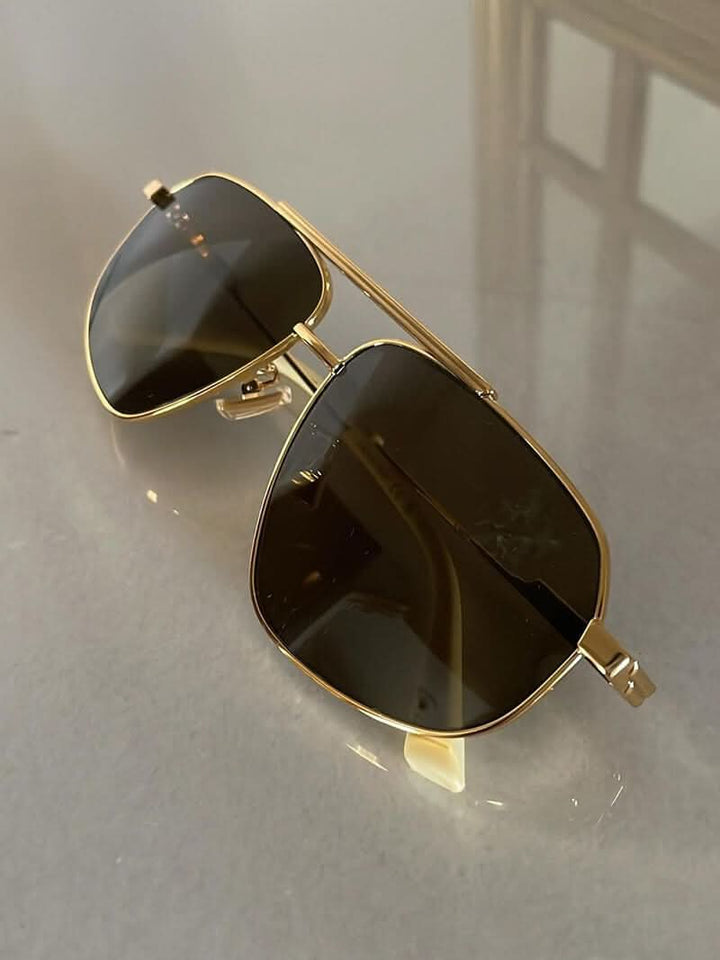 A woman wearing lightweight gold polarised sunglasses on a bright coastal day.