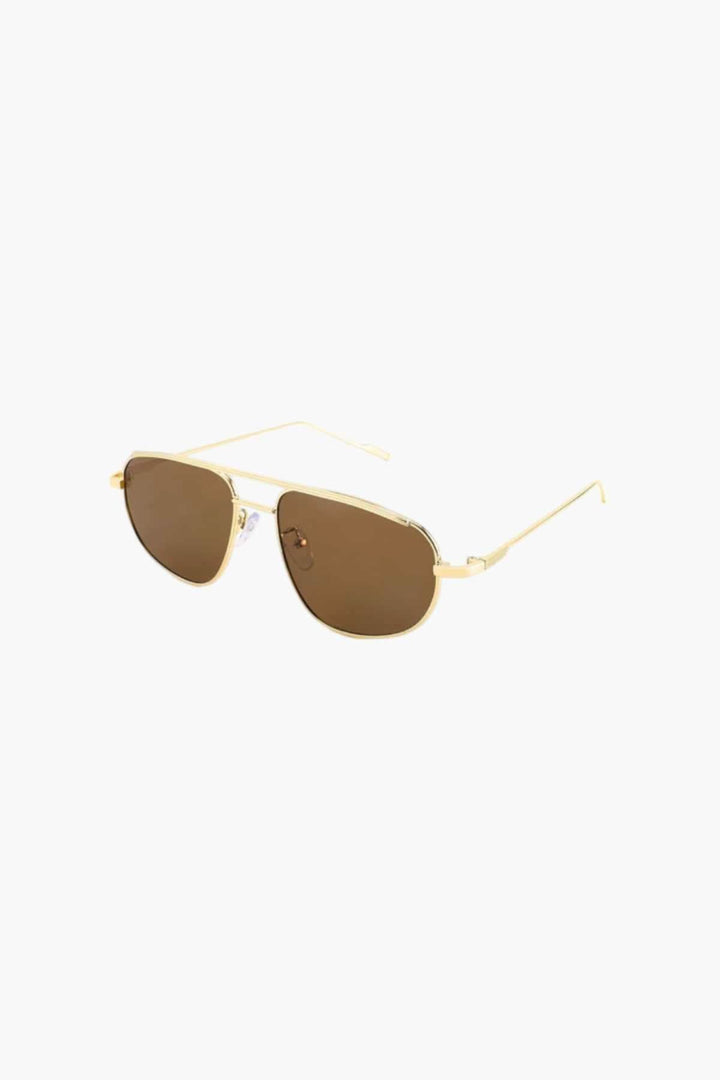 A woman wearing lightweight gold polarised sunglasses on a bright coastal day.