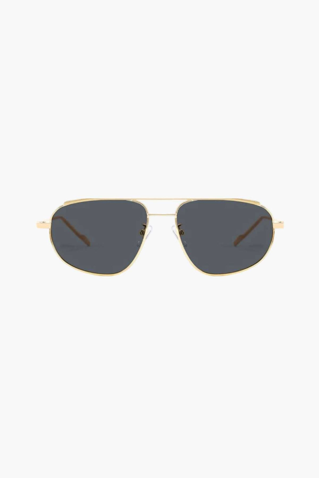 A woman wearing lightweight gold polarised sunglasses on a bright coastal day.