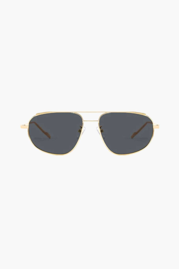 A woman wearing lightweight gold polarised sunglasses on a bright coastal day.