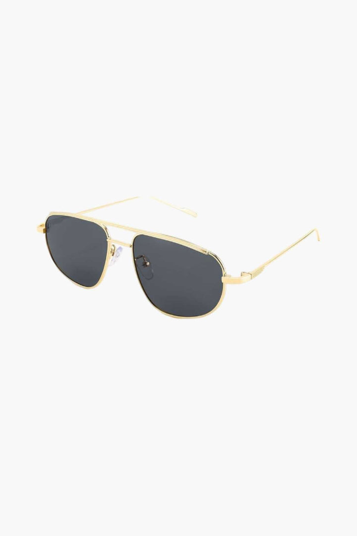 A woman wearing lightweight gold polarised sunglasses on a bright coastal day.
