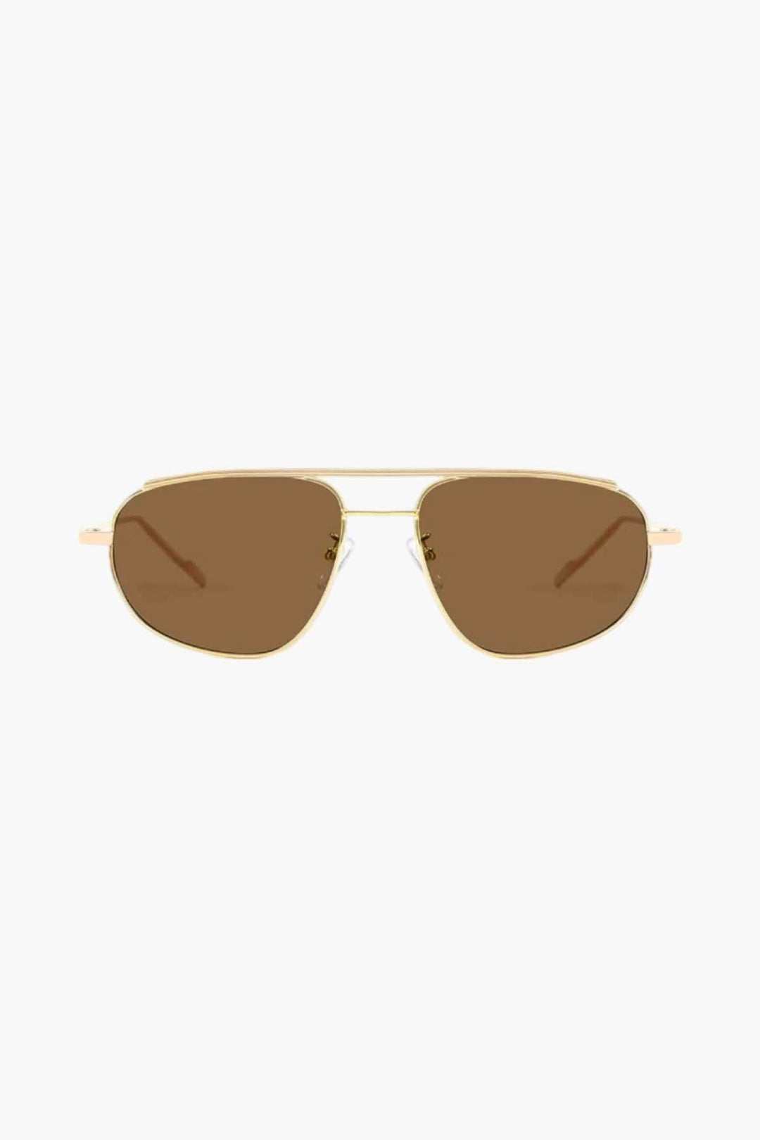 A woman wearing lightweight gold polarised sunglasses on a bright coastal day.