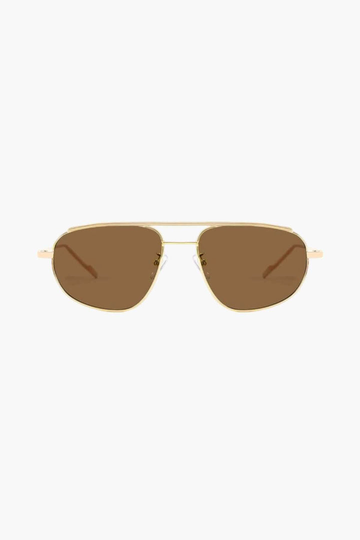 A woman wearing lightweight gold polarised sunglasses on a bright coastal day.