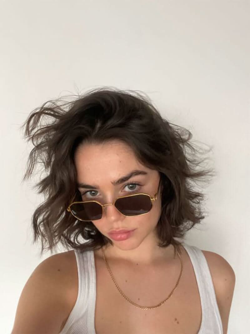 A woman wearing vintage-style gold polarised sunglasses on a sunny day out.