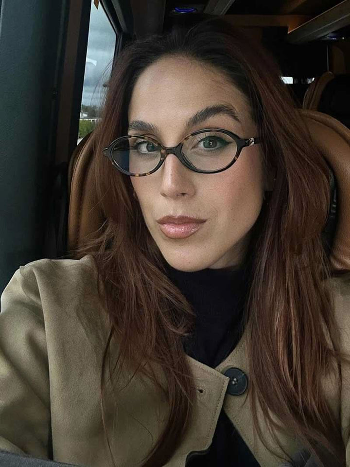 A woman wearing minimalist blue-light reading glasses while relaxing at home.