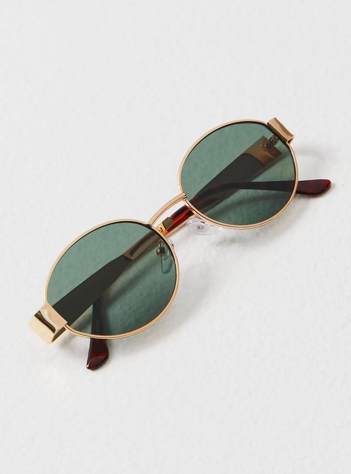 A woman wearing elegant vintage-style gold sunglasses on a sunny day out.