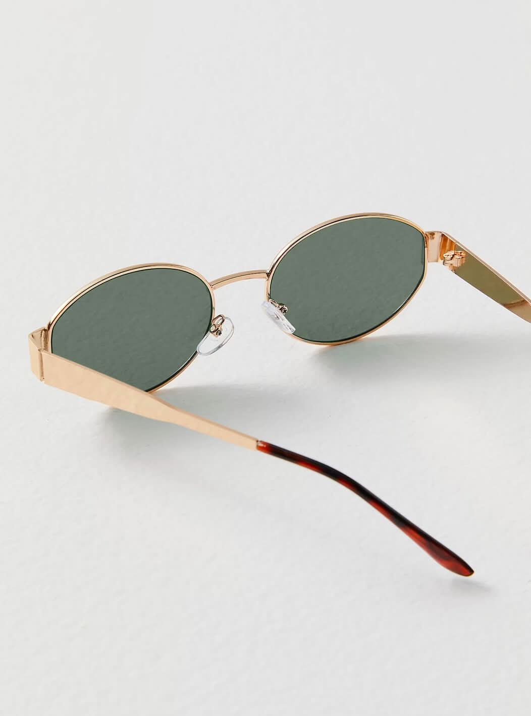 A woman wearing elegant vintage-style gold sunglasses on a sunny day out.