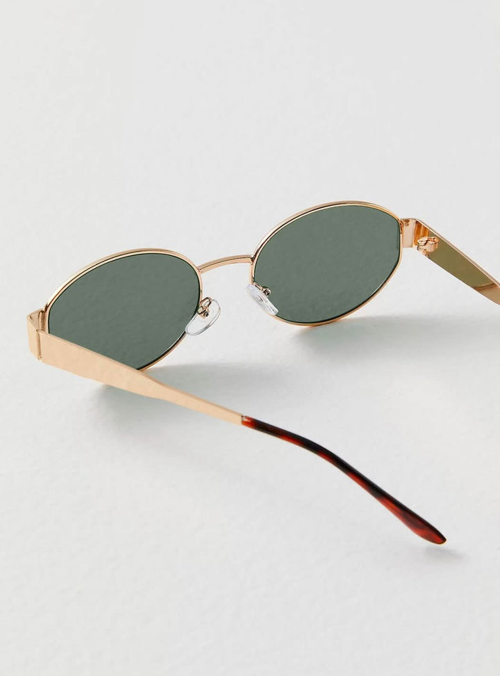 A woman wearing elegant vintage-style gold sunglasses on a sunny day out.
