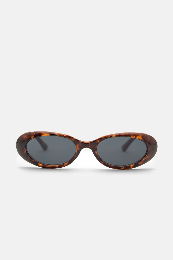 A woman wearing oval retro sunglasses while out shopping on a sunny day.