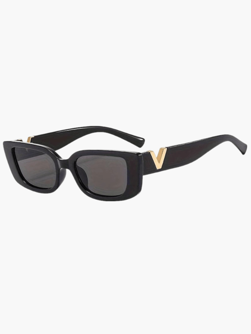 A woman at an outdoor event wearing chunky black rectangular retro sunglasses with a gold-tone accent.
