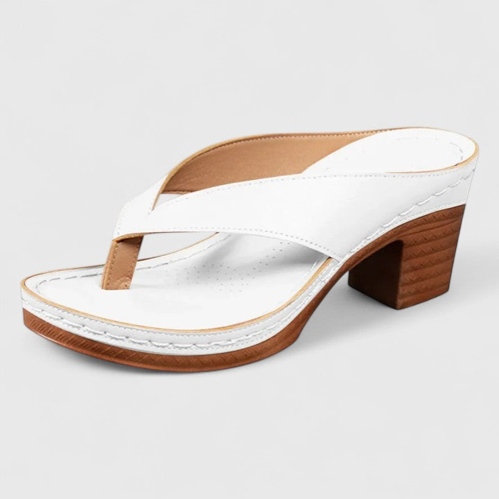 A woman in black open toe-post sandals with a chunky squared heel, walking easily through an evening event.