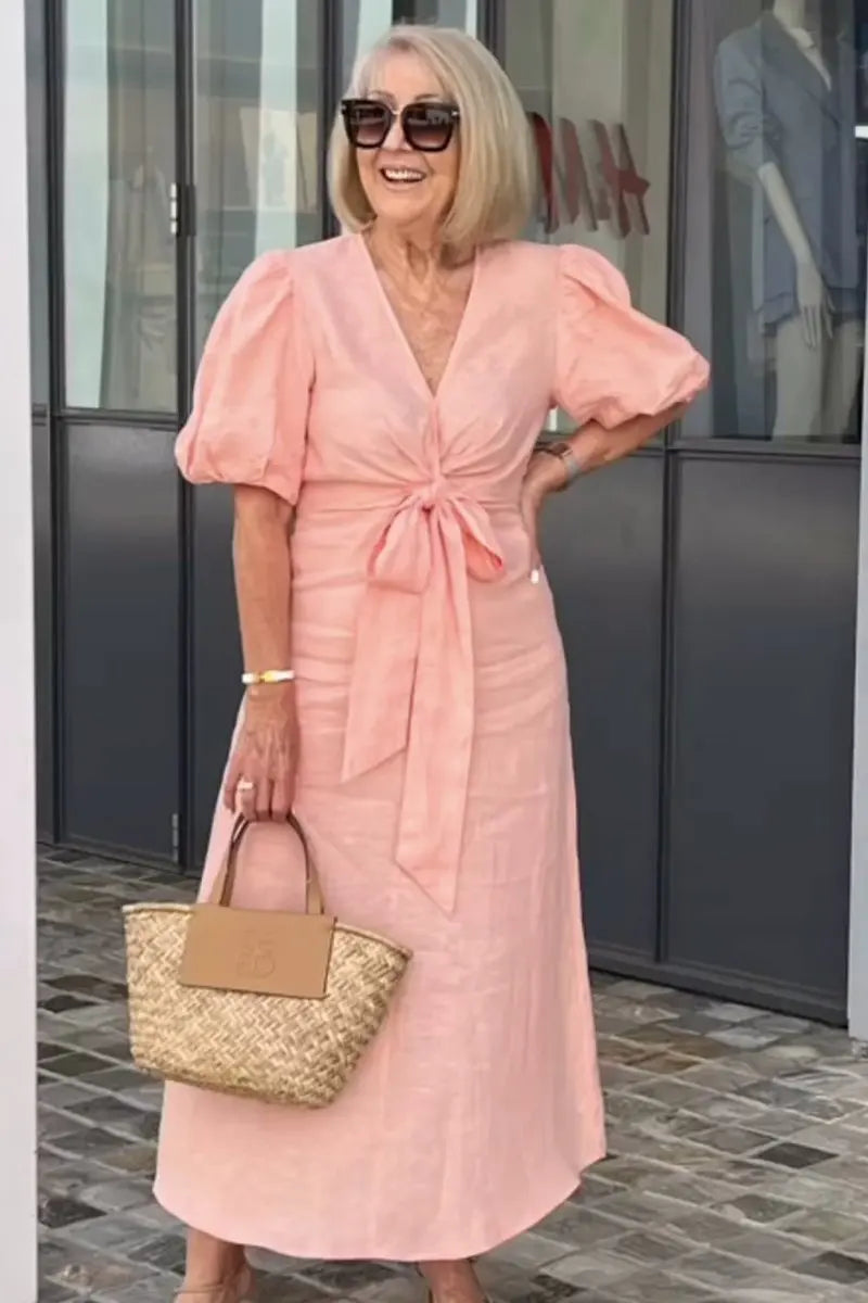 Woman wearing the Christina bow-front midi dress with puff sleeves at a garden party.