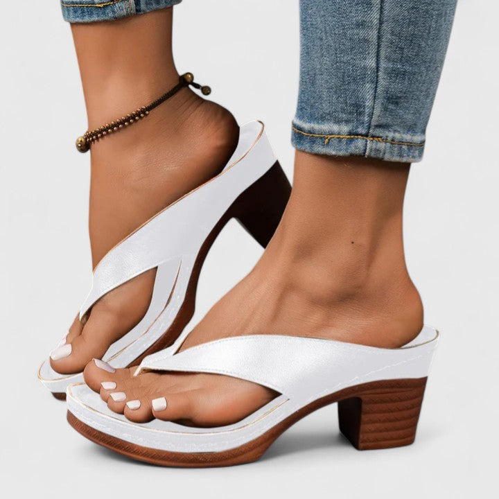 A woman in black open toe-post sandals with a chunky squared heel, walking easily through an evening event.