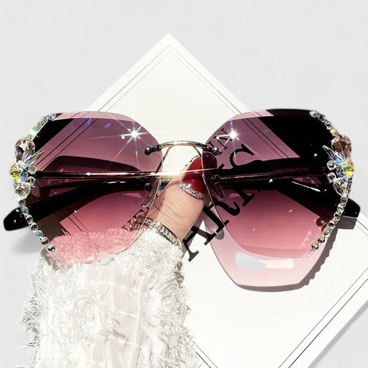 A woman at a special occasion wearing rimless sunglasses with sparkling diamanté accents, catching the light.