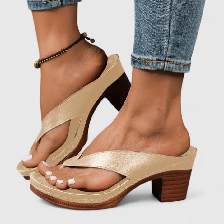 A woman in black open toe-post sandals with a chunky squared heel, walking easily through an evening event.