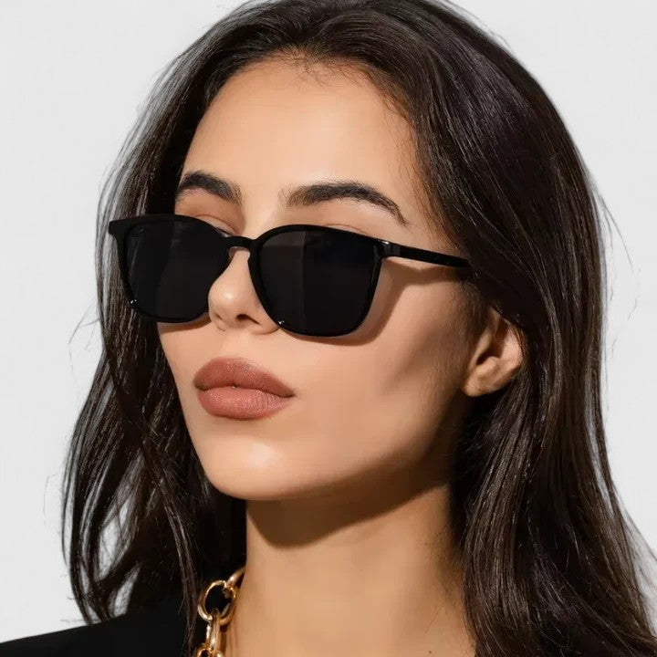 A woman on a sunny day wearing rectangular retro sunglasses, relaxed and stylish.