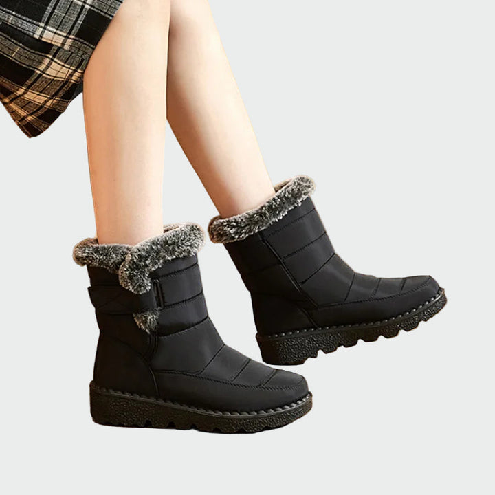 A woman on a frosty morning wearing warm deep navy winter boots with a grippy sole.
