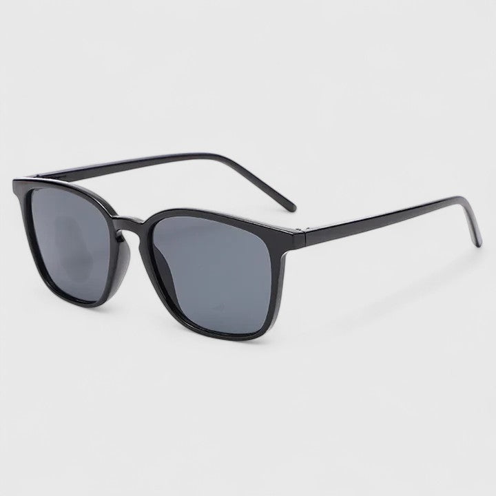 A woman on a sunny day wearing rectangular retro sunglasses, relaxed and stylish.
