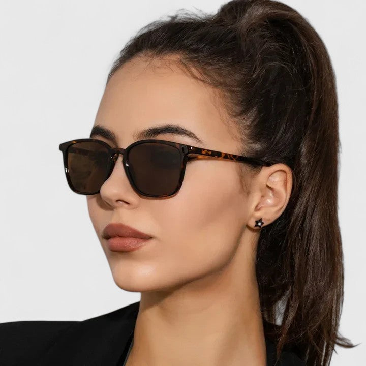 A woman on a sunny day wearing rectangular retro sunglasses, relaxed and stylish.