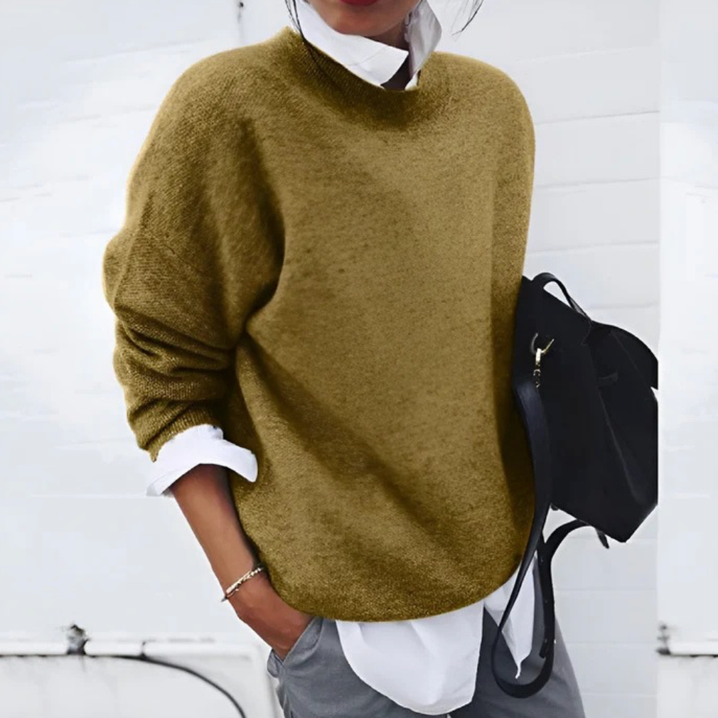 A woman wearing a soft mustard round-neck sweater with an elegant modern shape, relaxed and warm.