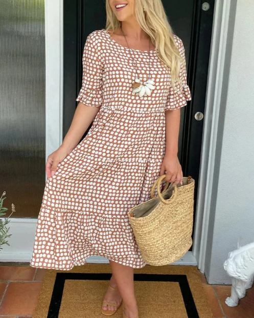 A woman wearing the Tammy short sleeve midi dress with a flowing skirt on a warm day.