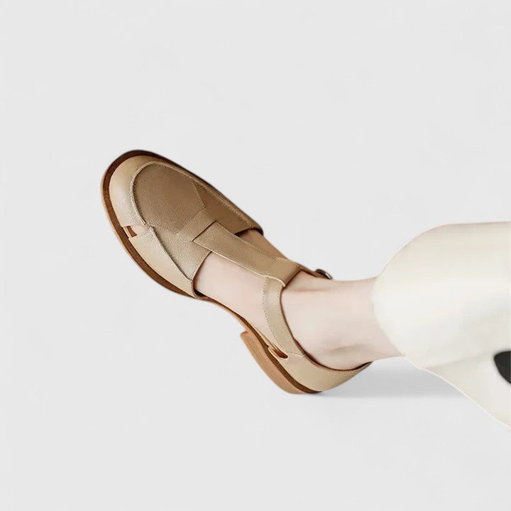 Woman wearing beige strapped Mary Jane sandals on a sunny terrace.
