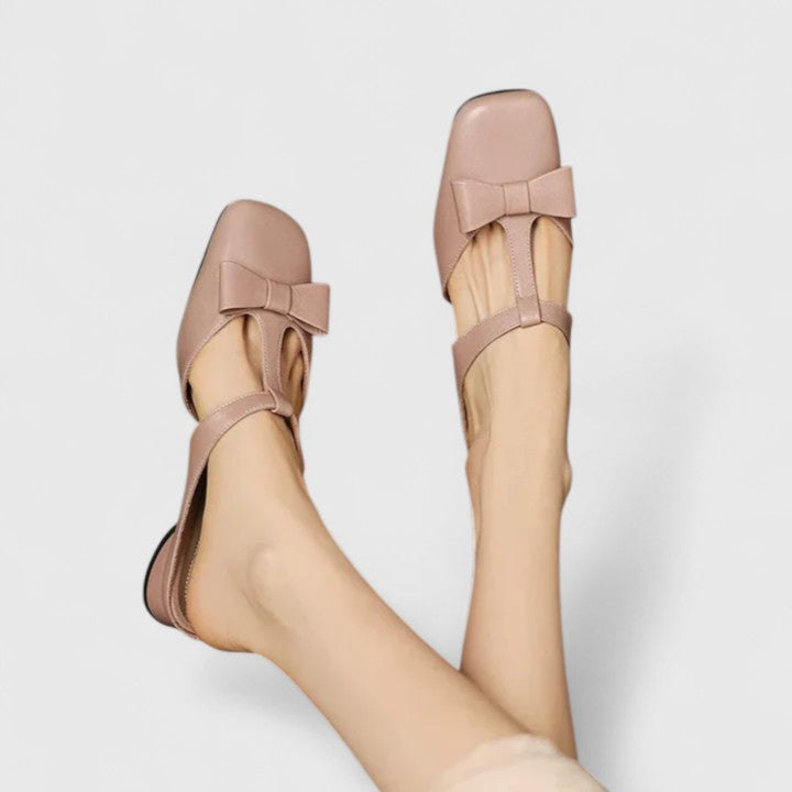 Soft green bow-detail mules with a slim T-strap, open back and a low heel.