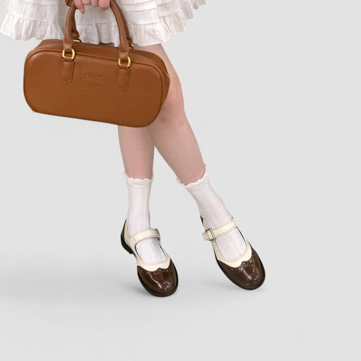 A woman wearing two-tone black and cream Mary Jane shoes, steady and comfortable on an evening out.