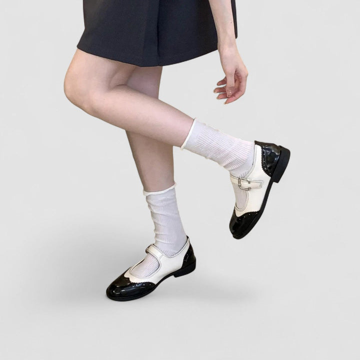 A woman wearing two-tone black and cream Mary Jane shoes, steady and comfortable on an evening out.