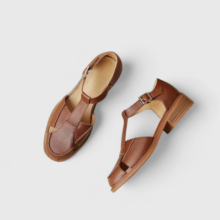 Woman wearing beige strapped Mary Jane sandals on a sunny terrace.