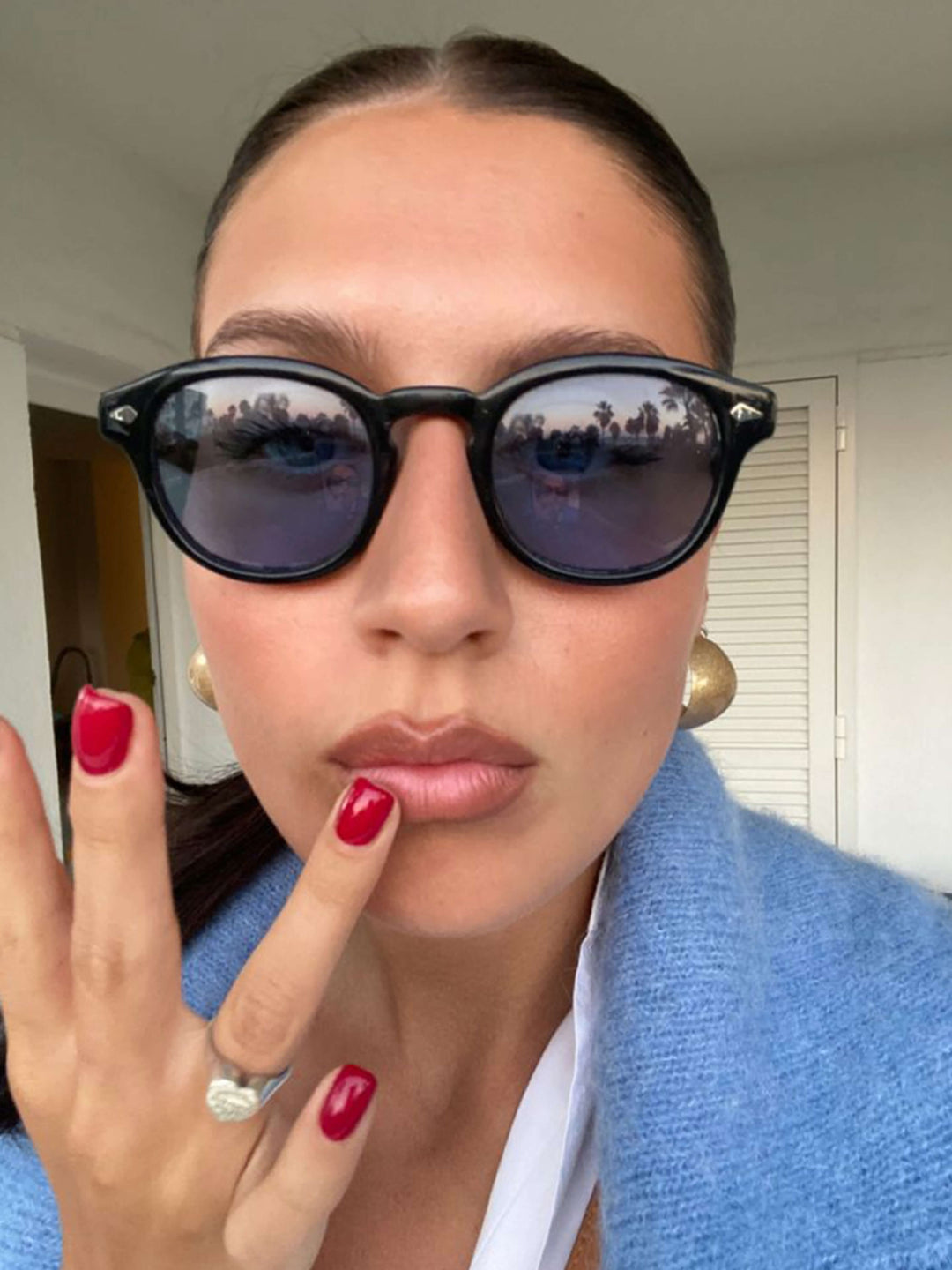 A woman wearing chic round-frame sunglasses on a city walk.
