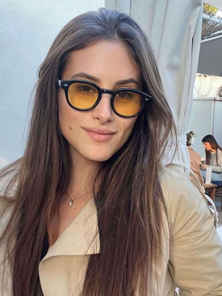 A woman wearing chic round-frame sunglasses on a city walk.