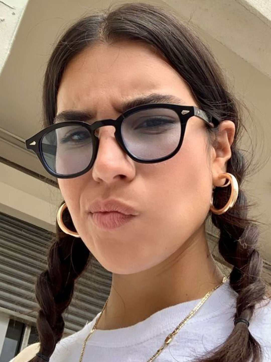 A woman wearing chic round-frame sunglasses on a city walk.