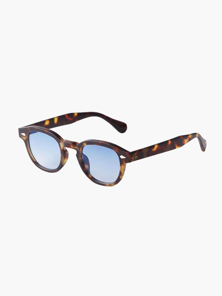 A woman wearing chic round-frame sunglasses on a city walk.