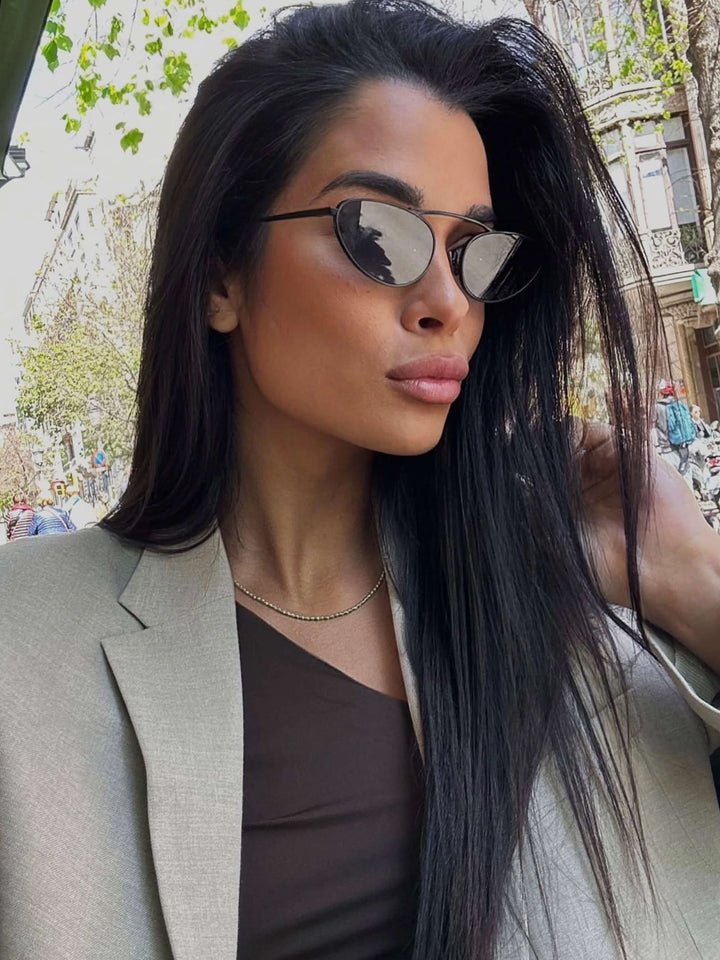 A woman wearing timeless slim black cat-eye sunglasses on an fall day.