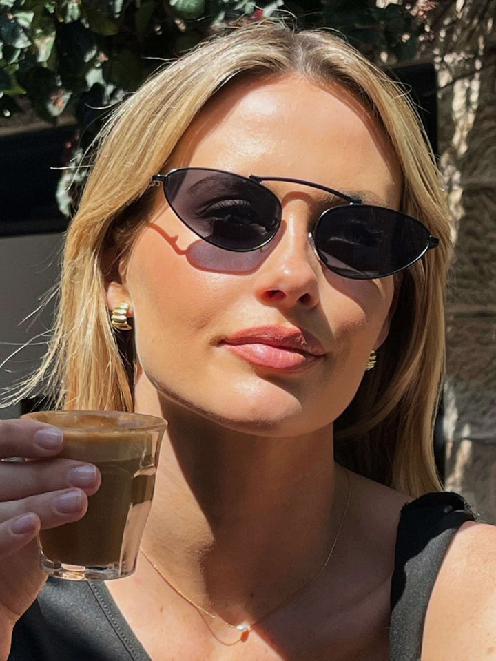 A woman wearing timeless slim black cat-eye sunglasses on an fall day.