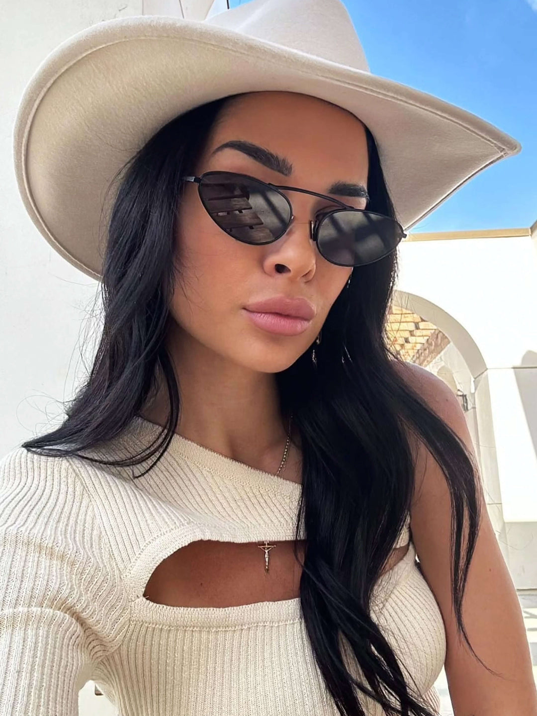 A woman wearing timeless slim black cat-eye sunglasses on an fall day.
