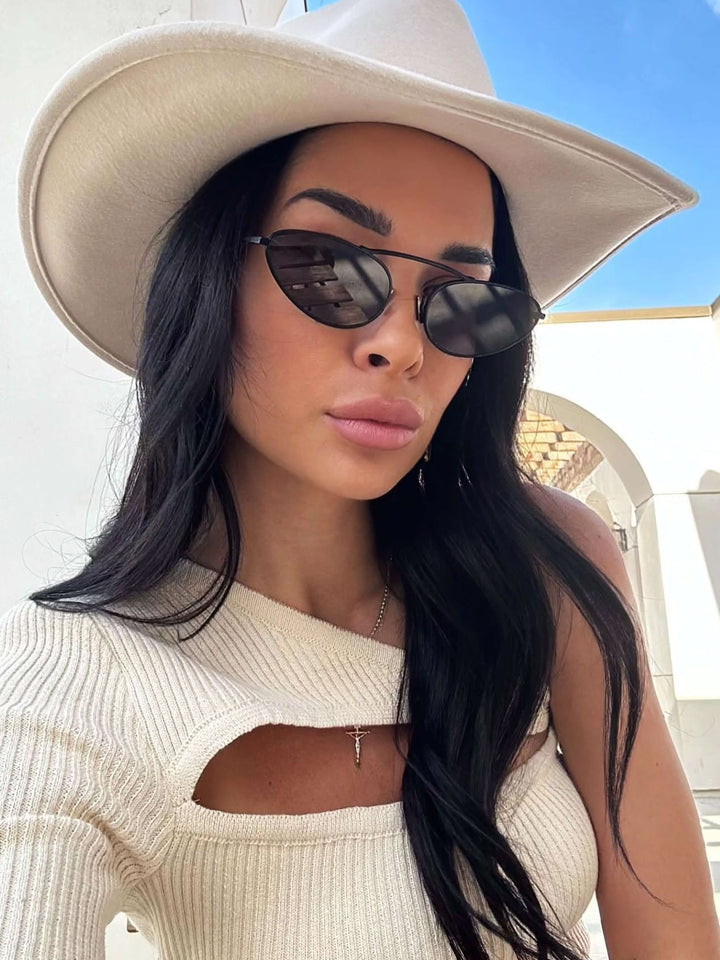 A woman wearing timeless slim black cat-eye sunglasses on an fall day.