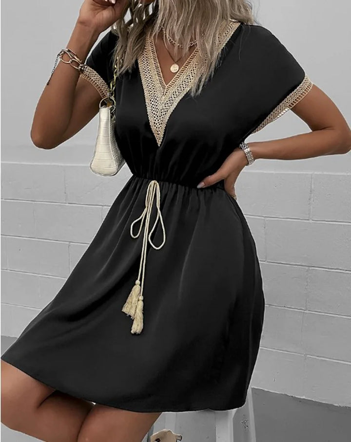 A woman wearing a relaxed boho dress with fringe accents and delicate openwork detailing.