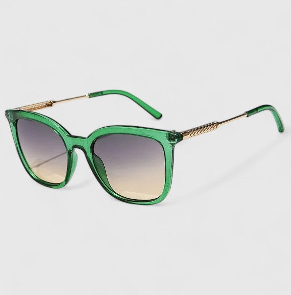 A woman on a coastal walk wearing oversized retro sunglasses, relaxed in the bright sun.