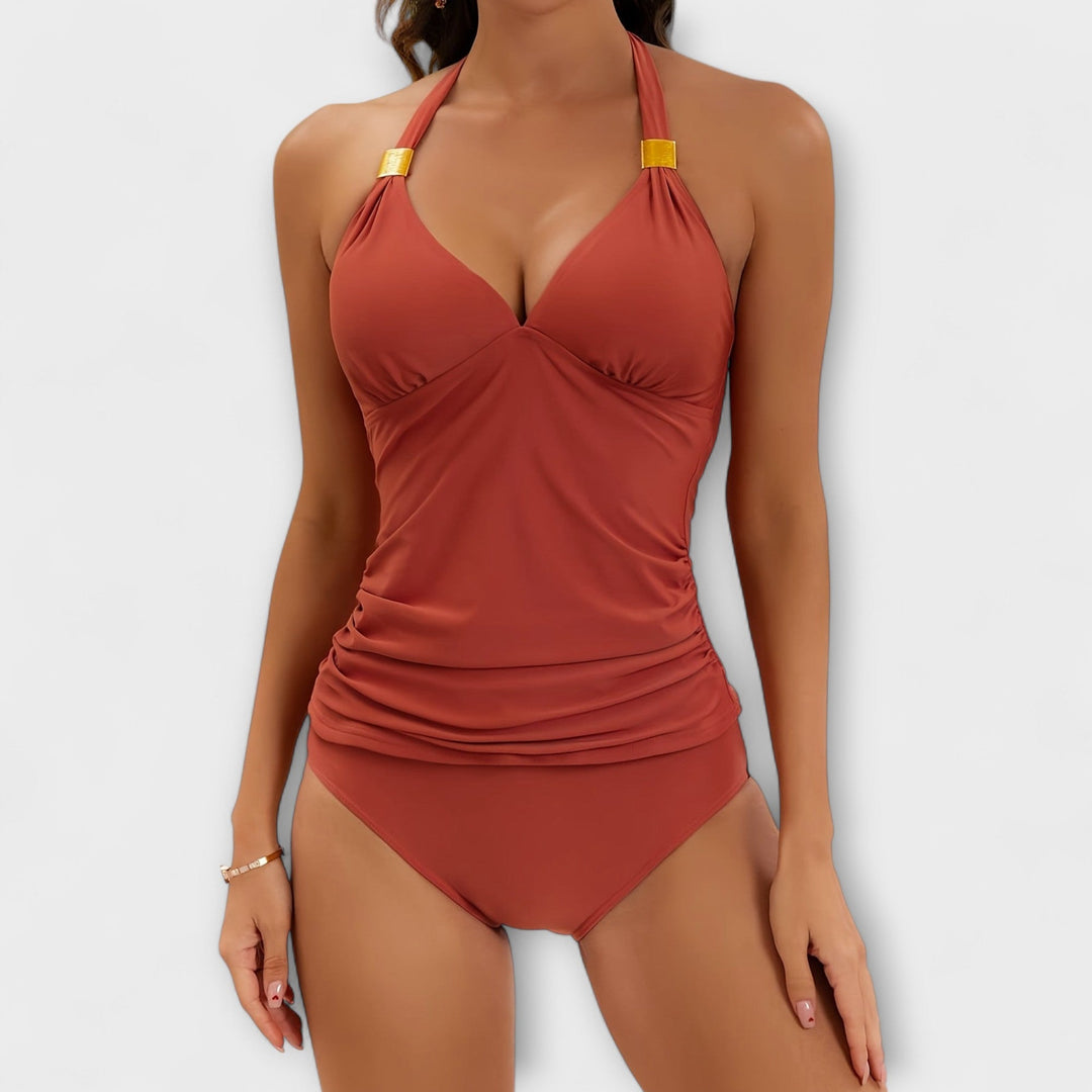 A woman by the water in a solid-colour two-piece halter swimsuit, relaxed and confident in the sun.