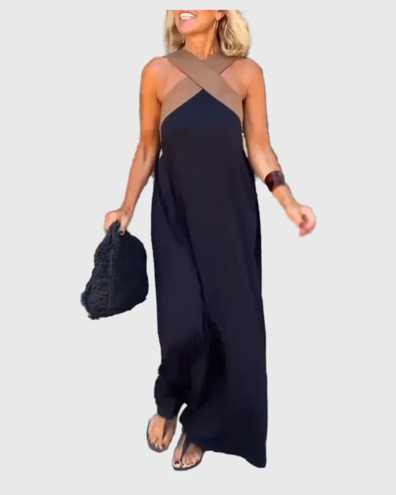 Woman wearing the Julie halterneck maxi dress in navy with a contrast crossover neckline, walking outdoors.